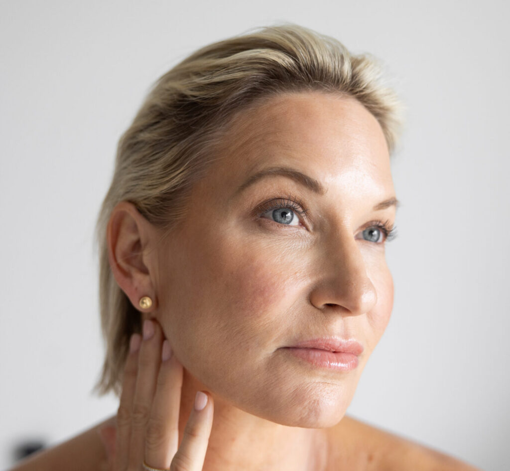 woman with blonde hair touching her face