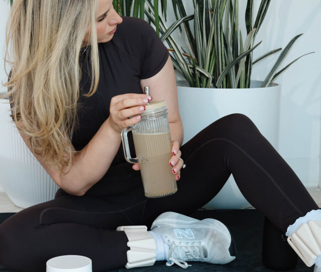 Women sitting on a yoga mat with an iced coffee